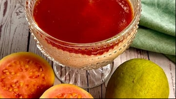 Mousse de goiabada servida em uma taça de sobremesa, acompanhada de dois pedaços de goiabada cortados ao meio e uma goiabada inteira ao lado, tudo sobre uma mesa de madeira. Foto: Luciana Bonometti/ Arquivo pessoal